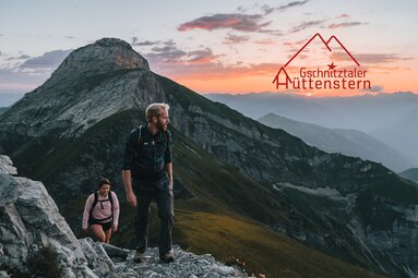 Zwei Wanderer auf dem Weg zur Kirchdachspitze mit Hüttenstern Logo | © TVB Wipptal / Johannes Bitter