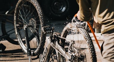Ein Mann spritzt sein Mountainbike mit Wasser ab | © TVB Wipptal | Johannes Bitter