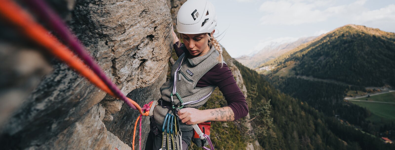 eine Sportlerin hängt am Seil in einer Felswand und hantiert mit einer Expressschlinge | © TVB Wipptal | Johannes Bitter