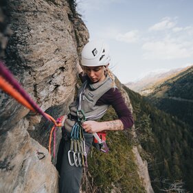 eine Sportlerin hängt am Seil in einer Felswand und hantiert mit einer Expressschlinge | © TVB Wipptal | Johannes Bitter