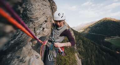 eine Sportlerin hängt am Seil in einer Felswand und hantiert mit einer Expressschlinge | © TVB Wipptal | Johannes Bitter