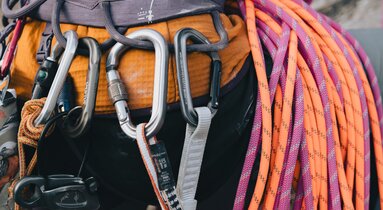 Nahaufnahme einer Person von hinten, die einen Klettergurt - ausgestattet mit Seilen und trägt.  | © TVB Wipptal | Johannes Bitter
