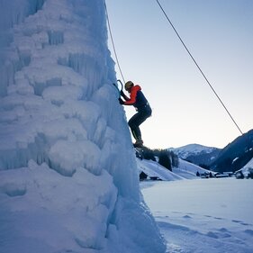 Ein Eiskletterer hängt mit seinen Eisgeräten am Eisturm | © Christoph Staud