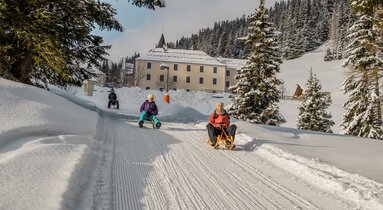 Zwei Rodler ziehen ihre Rodel die Rodelbahn hinauf zur Maria Waldrast | © TVB Wipptal | Joakim Strickner