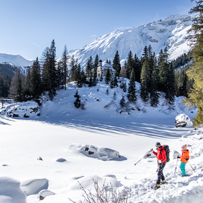 Ein Mann und ein Kind stehen am Rand des verschneiten Obernberger Sees mit ihren Schneeschuhen an den Füßen | © Ewelina Herzog