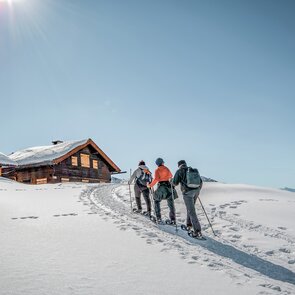 Eine Kleingruppe wandert mit Schneeschuhen zu einer Hütte | © TVB Wipptal | Judith Hammer