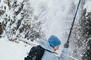 eine Schneeschuhgeherin steht unter einer mini Baumlawine und wird eingeschneit | © TVB Wipptal | Johannes Bitter