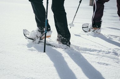 Nahaufname der Beine von zwei Schneeschuhwanderern, die durch den Tiefschnee stapfen. | © TVB Wipptal | Johannes Bitter