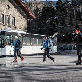 Drei Personen gehen mit den Tourenskiern auf den Schultern und in Skikleidung zum Bahnhof in Steinach | © TVB Wipptal / Susanne Kraft