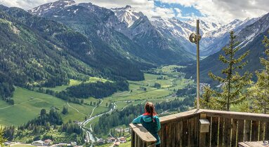Eine Frau steht auf der Aussichtsplattform und schaut taleinwärts ins Tal hinunter | © TVB Wipptal | Judith Hammer