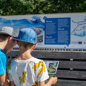 Zwei Kinder schauen sich das Prospekt vom Wasserweg vor einer Infotafel an | © TVB Wipptal | Judith Hammer
