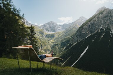 Ein Mann liegt auf einer Liege bei St. Magdalena und schaut in die Berglandschaft hinaus | © TVB Wipptal | Johannes Bitter