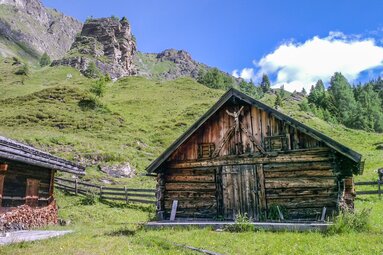 Sonnenverbrannte Almhütte mit dem Fels im Hintergrund | © Helga Beermeister