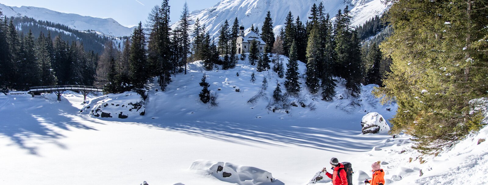 Mann mit Kind geht mit Schneeschuhen am Rand des Sees. | © Ewelina Wild