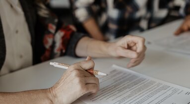 Person hält eine Stift in der Hand, vor ihr liegt ein Blatt Papier | © TVB Wipptal / Victoria Hörtnagl