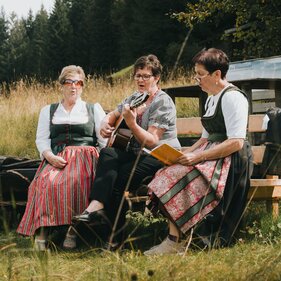 Drei Frauen sitzen auf einer Bank und musizieren gemeinsam | © Tourismusverband Wipptal | Johannes Bitter  