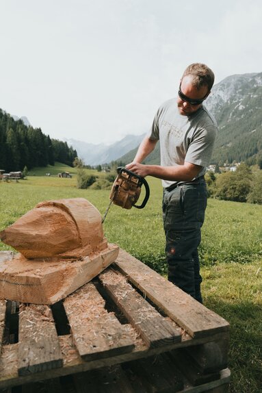 Ein Mann schnitzt mit einer Motorsäge an einem Stück Holz | © TVB Wipptal | Johannes Bitter