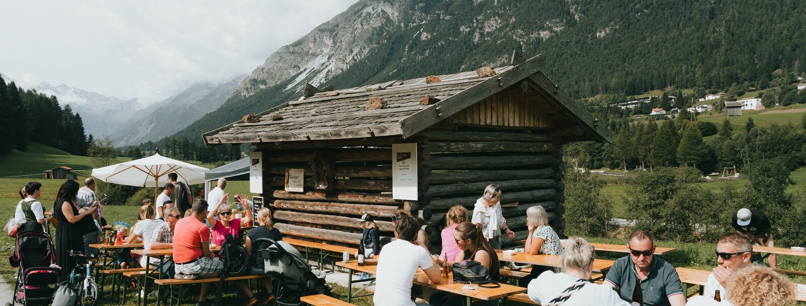 Leute sitzen gemütlich auf Bierbänken vor einem Stadl | © TVB Wipptal | Johannes Bitter