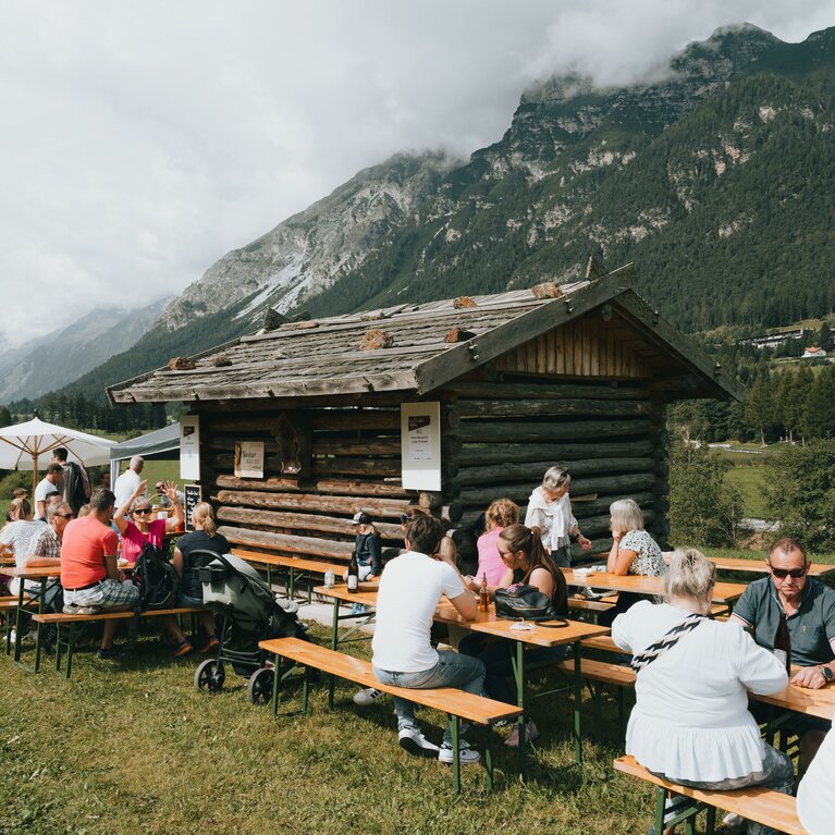 Leute sitzen gemütlich auf Bierbänken vor einem Stadl | © TVB Wipptal | Johannes Bitter