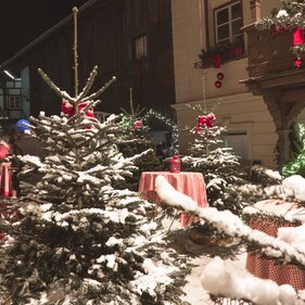 Stehtische zwischen angeschneiten Weihnachtsbäumen im historischen Dorfkern von Matrei | © Kreativstadl