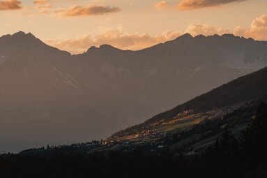 An einem Hang gelgene Häusersiedlung bei Sonnenuntergang | © TVB Wipptal | Johannes Bitter