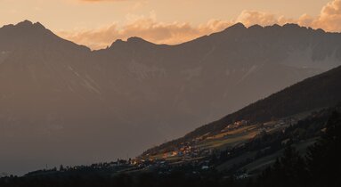 An einem Hang gelgene Häusersiedlung bei Sonnenuntergang | © TVB Wipptal | Johannes Bitter