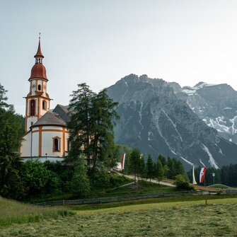 Eine Barockkirche steht auf einer leichten Anhöhung inmitten von Feldern und W | © Christoph Partsch