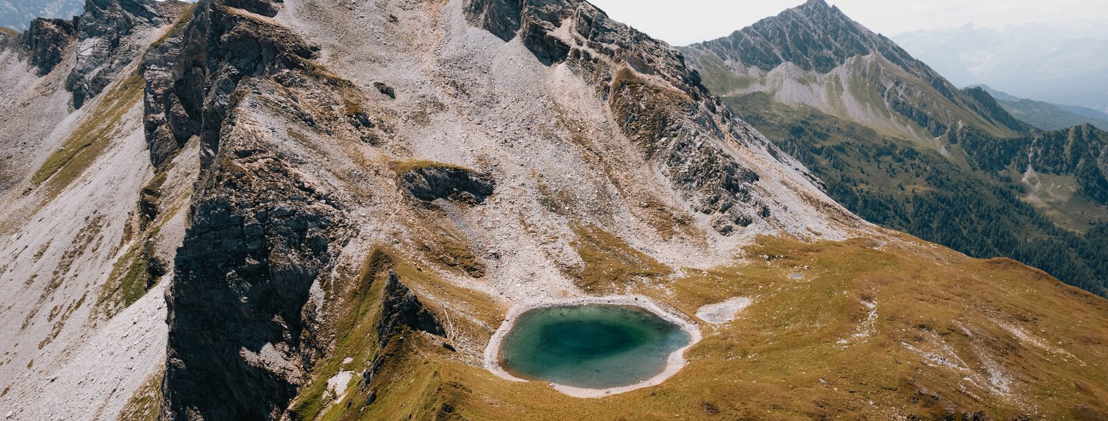 Ein Bergsee am Fuß von markanten Bergspitzen, aufgenommen aus der Vogelperspektive | © TVB Wipptal | Johannes Bitter