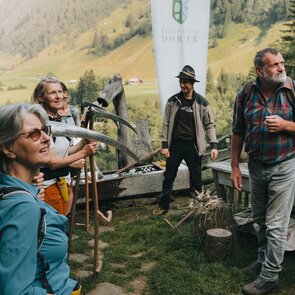 Eine Gruppe von Menschen vor einer Almhütte blickt gespannt zu Berg | © TVB Wipptal | Johannes Bitter