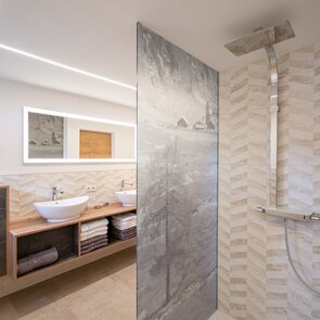 Modernes Badezimmer mit Doppelwaschtisch und bedruckter Duschwand | © TVB Wipptal | Judith Hammer